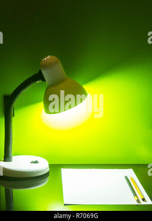 Lampe und Papier mit Bleistift auf grüne Wand Stockfoto