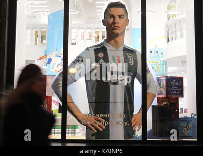 Kiew, Ukraine. 7 Dez, 2018. Eine Frau geht Vergangenheit ein großes Plakat mit einem Bild von Juventus Turin der Stürmer Cristiano Ronaldo von Portugal, eine Werbung für FIFA 19 Videospiel für PlayStation, durch das Fenster eines Shop in Kiew, Ukraine gesehen, am 7. Dezember 2018. Credit: Serg Glovny/ZUMA Draht/Alamy leben Nachrichten Stockfoto