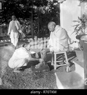 Kasturba Gandhi wäscht ihrem Mann Mahatma Gandhi die Füße, hinter Sardar Vallabhbhai Patel, Bardoli, Gujarat, Indien, 1939, Altes Vintage 1900er Bild Stockfoto