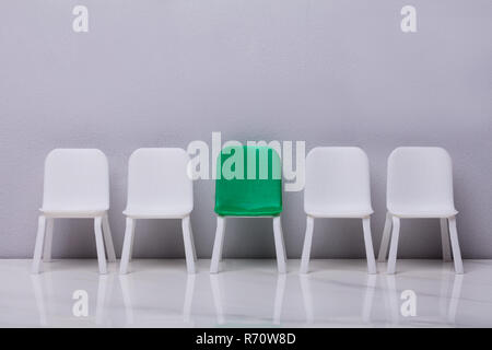 Leeren kleinen Stuhl in der Zeile auf grauem Hintergrund Stockfoto