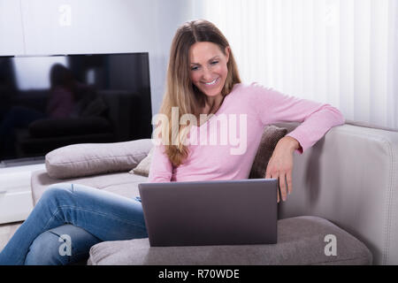 Glückliche Frau mit Laptop zu Hause Stockfoto