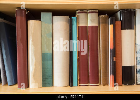 Viele alte staubige Bücher in einer Bibliothek auf einem hölzernen Regal Stockfoto