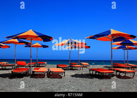 Bunte Liegestühle und Sonnenschirme am Strand, blaues Meer, Kreta, Griechenland Stockfoto