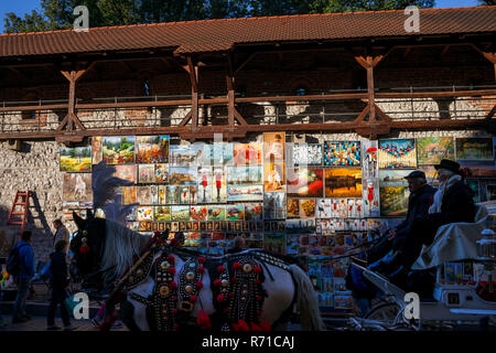 Gemälde zum Verkauf an der Wand und Kutsche auf Sightseeing Tour in der Altstadt von Krakau in Polen angezeigt, Europa Stockfoto