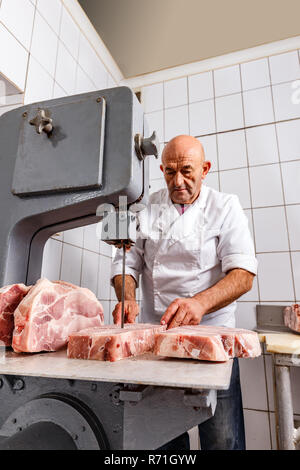 Metzger schneiden von Fleisch mit bandsäge Metzgerei Stockfoto