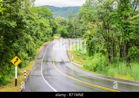 Nassen Berg Asphaltstraße nach dem Regen mit verkehrsschild von scharfen Kurven Zeichen rückwärts Stockfoto