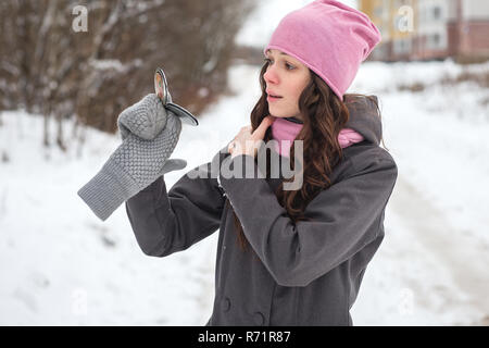 Schöne junge Mädchen schaut in den Spiegel und preens im Winter im Freien. Stockfoto