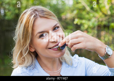 Glückliche junge Frau im Garten halten eine Handvoll reife Pflaumen Stockfoto