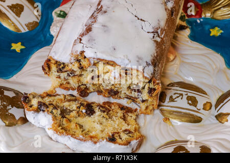 Stollen Weihnachten traditionelle deutsche Marzipan Kuchen auf einem Teller. Saisonale Früchte Brot mit Nüssen, Gewürzen und Puderzucker mit einer Scheibe abschneiden auf einem Teller. Stockfoto