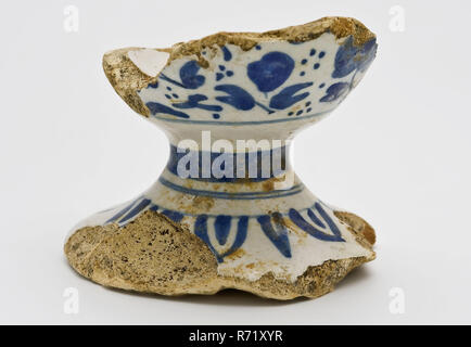 Fuß aus Fayence Senf Topf, mit Blumenmotiv auf weißem Hintergrund eingerichtet, Senf pot pot Geschirr Inhaber fragment Steingut Keramik Steingut Glasur Glasur Zinn, von Hand gedreht Fried glasiert lackiert gebackene Fuß aus Fayence Senf pot. Blaue Blume Einrichtung auf dem Bauch. Linien um die Verengung des Fußes und Blatt zahlen rund um den Fuß Oberfläche mit ausgeschnittenen Seele Gelblich shard Archäologie Stadtzentrum Stadsdriehoek Rotterdam Laurens Kirche indigenen Töpferei Senf mit Boden Entdeckung bei der Restaurierung der in Rotterdam Laurenskerk Ausgrabung östlich der Kirche dienen. Stockfoto