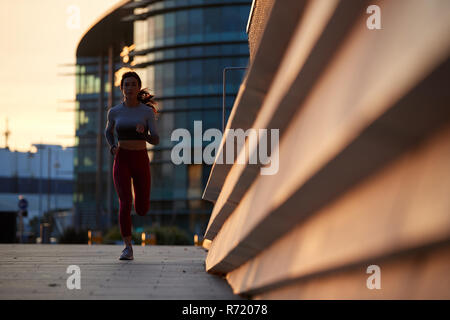 Single kaukasischen Frauen Joggen in einem Stadtzentrum bei Sonnenuntergang Stockfoto