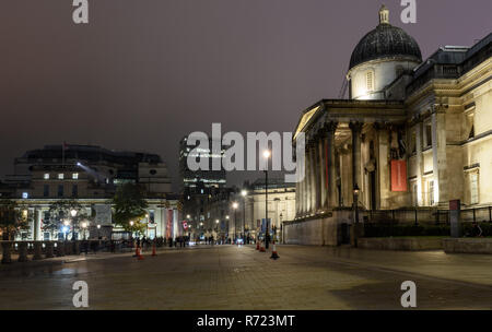 London, England, UK - 15. Oktober 2018: Fußgänger auf dem Londoner Trafalgar Square bei Nacht, alingside der National Gallery und Kanada Haus, Stockfoto