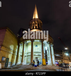 London, England, UK - 12. Oktober 2018: Fußgänger und Fahrzeuge passieren Kirche All Souls, nachts beleuchtet, an der Spitze des Londoner Regent's Street. Stockfoto