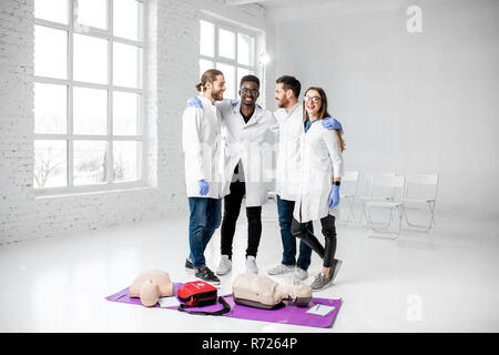 Portrait einer jungen Mannschaft der Mediziner in einheitlichen ständigen zusammen mit medizinischen Material nach der Erste Hilfe Ausbildung in den weißen Klassenzimmer Stockfoto