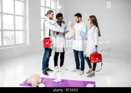 Portrait einer jungen Mannschaft der Mediziner in einheitlichen ständigen zusammen mit medizinischen Material nach der Erste Hilfe Ausbildung in den weißen Klassenzimmer Stockfoto