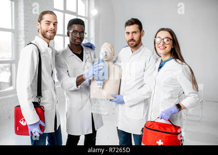 Portrait einer jungen Mannschaft der Mediziner in Uniform stehen zusammen, nachdem die Erste Hilfe Ausbildung in den weißen Klassenzimmer Stockfoto