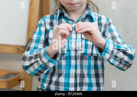 Blonde junge formt aus Knetmasse zu Hause am Tisch. Die Idee und das Konzept der Schule, Schule, Home Bildung und entwicklungspolitischen Aktivitäten. Stockfoto