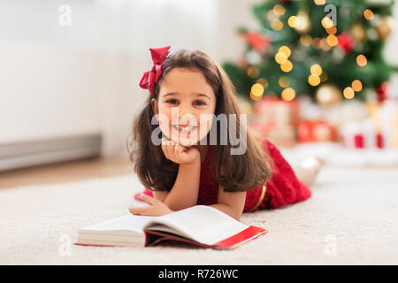 Happy girl lesen Buch zu Hause an Weihnachten Stockfoto