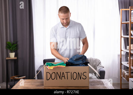 Junger Mann Spenden Kleider Spenden über Holz- Schreibtisch