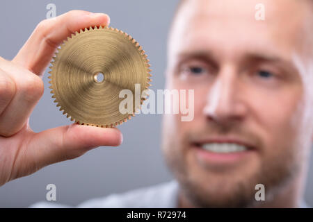 Close-up In eines Mannes Hand und Goldene Zahnrad Stockfoto
