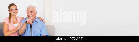 Panoramablick von lächelnden älteren Mann mit seiner Enkelin Sitzen auf einem Sofa Stockfoto
