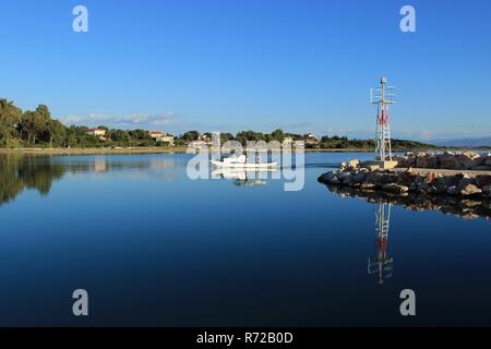 Kleine weiße hölzerne Fischerboote Einlaufen in einen Hafen von Koronisia Dorf in Ambracian Golf in Griechenland in der Nähe von ein Leuchtfeuer im Sommer Stockfoto