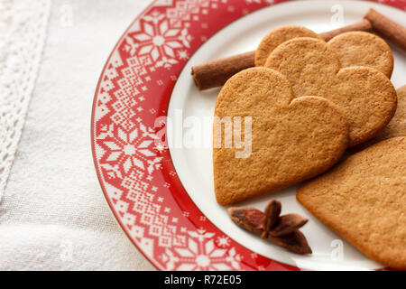 Lebkuchen heart-shaped Cookies mit Zimtstangen und Anis Sterne auf rote Platte Stockfoto