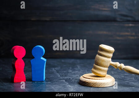 Holzfiguren von ein Mann und eine Frau stehen in der Nähe des Richters Hammer. Ungleichheit Konzept: Gender Pay Gap. Scheidung. Aufteilung des Eigentums vor Gericht. Stockfoto