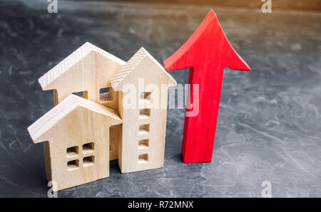 Holzhäuser mit einem roten Pfeil nach oben. Konzept der hohe Nachfrage nach Immobilien. zur Steigerung der Energieeffizienz der Wohnungen. Anstieg der Immobilienpreise. Eigentum. Bevölkerung Stockfoto