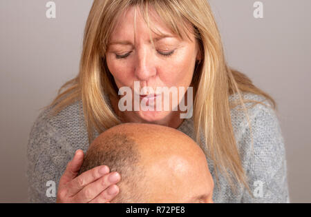 Frau küssen ist ein Mann balding Kopf Stockfoto