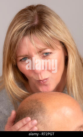 Frau küssen ist ein Mann balding Kopf Stockfoto