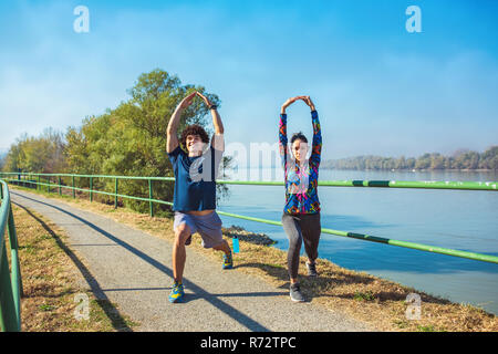 Junge fitness Mann und Frau, die sich in den Park. Junges Paar Erwärmung bis in den Morgen. Stockfoto