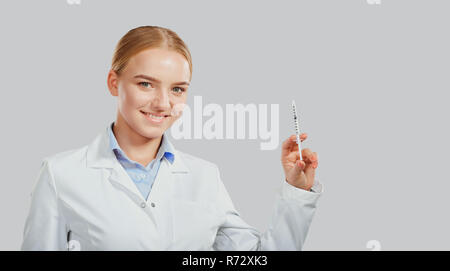 Frau Doktor mit einer Spritze in der Hand auf den Hintergrund. Stockfoto