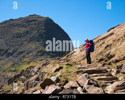 Eine weibliche Backpacker in Llangefni y Saethau auf Snowdon der Watkin Weg. Der Gipfel des Snowdon, Yr Wyddfa, Türme oben Stockfoto