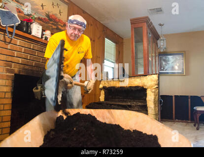 A Southern Baptist Katastrophenhilfe freiwillige Schaufeln Ruß aus einem Kamin nach einem Hochwasser in Baton Rouge, Louisiana. Stockfoto