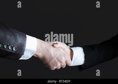Zwei Geschäftsleute (Mann ad Frau) die Hände schütteln, Low Key. Stockfoto