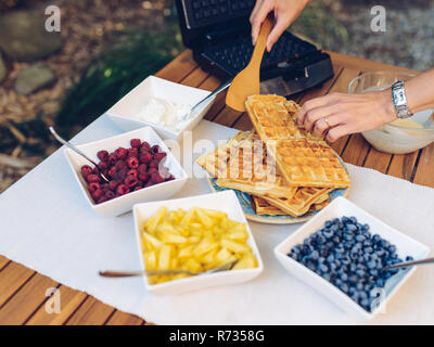 Zubereitung von hausgemachten Waffeln im Waffeleisen draußen im Garten Stockfoto