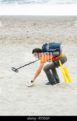 Savona, Italien, 25. Oktober 2018: Der Mann ist zu Fuß am Strand mit einem Metalldetektor in der einen Hand und ein Sieb in der anderen. Er versucht zu finden, Jewe Stockfoto