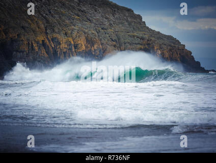 Ein Absturz wave während der großen Schwellen, in der Nähe der Felsen auf Porth Ceiriad Strand, in der Nähe von Abersoch, Wales, Großbritannien Stockfoto