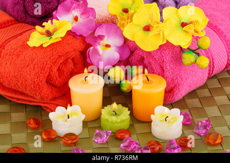 Bad mit Handtüchern, Kerzen und Blumen auf Bambus Hintergrund gesetzt. Stockfoto