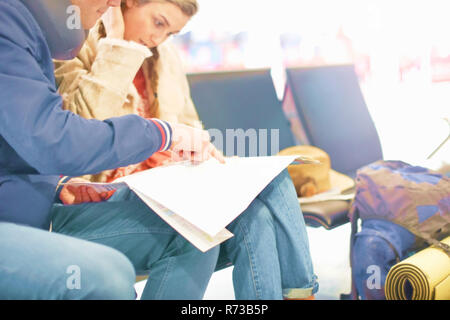 Junges Paar in Abflug Lounge sitzen, auf Karte suchen, Planung Reise, mittlere Partie Stockfoto