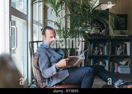 Mann Lesung am Sessel Stockfoto