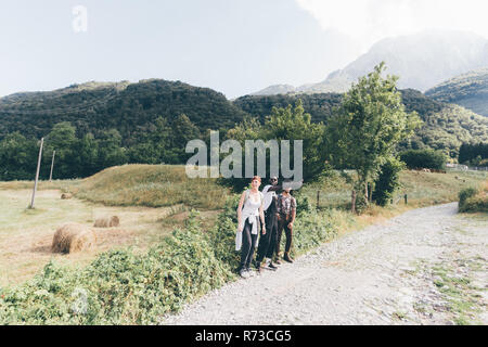 Jungen Erwachsenen Wanderer Freunde durchblättern heben auf den ländlichen Feldweg, Primaluna, Trentino-Südtirol, Italien Stockfoto