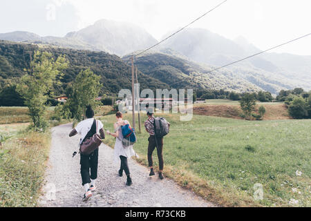 Drei junge erwachsene Freunde Wandern auf Feldweg, Rückansicht, Primaluna, Trentino-Südtirol, Italien Stockfoto