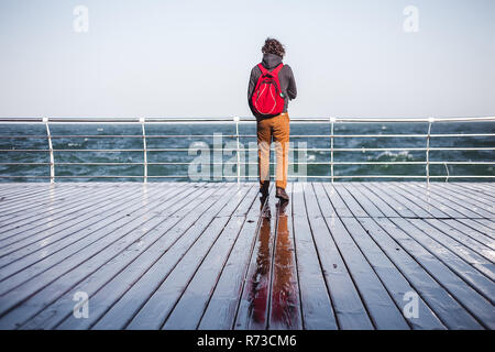 Mitte der erwachsene Mann mit Blick vom Pier zum Meer, Ansicht von hinten, Odessa, Odeska Oblast, Ukraine Stockfoto
