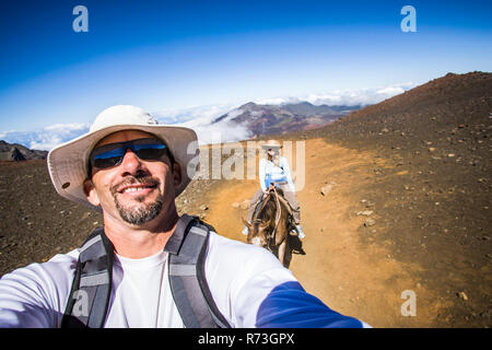 Ein Mann auf einem Pferd ein selfie von ihm und seiner Frau, Haleakala Krater Haleakala National Park, Maui, Hawaii. Stockfoto