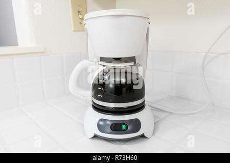 Kleine weiße Kaffeemaschine an sauberen, weißen Fliesen Arbeitsplatte in der Küche. Stockfoto