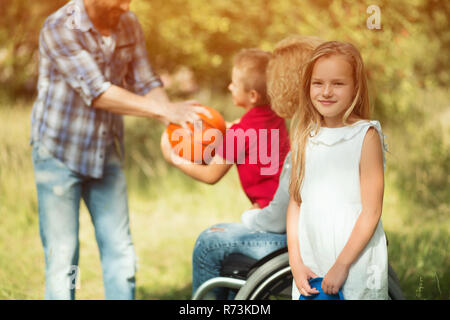 Kleine Tochter eines behinderten Frau lächelt an Kamera Stockfoto