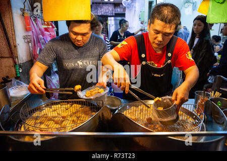 JIUFEN, TAIWAN - 6. NOVEMBER: Zwei Männer kochen stinky Tofu auf dem Nachtmarkt von Jiufen am 6. November 2018 in Jiufen, Taiawan. Stockfoto