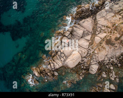 Luftaufnahmen der Sardinien Küste während eines Sommer Sonnenuntergang. Kleine Wellen auf den Felsen mit einer Drohne getroffen. Stockfoto